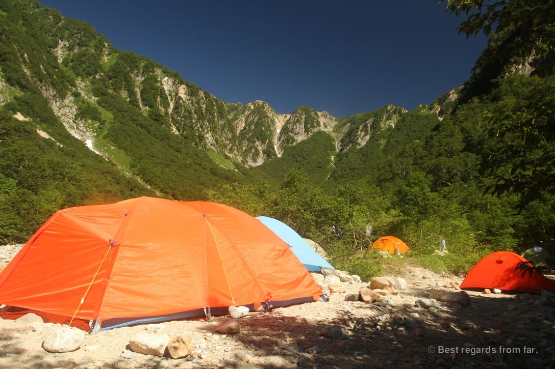 A high-altitude camp with colourful technical tents at the foot of the mountains, while hiking the Japanese Alps.