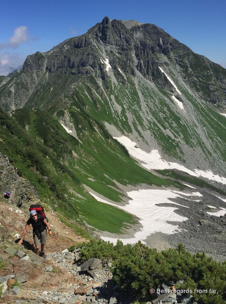 Hiker following the trail markers on the Daikiretto section while hiking the Japanese Alps. Mount Yari-dake in the background.