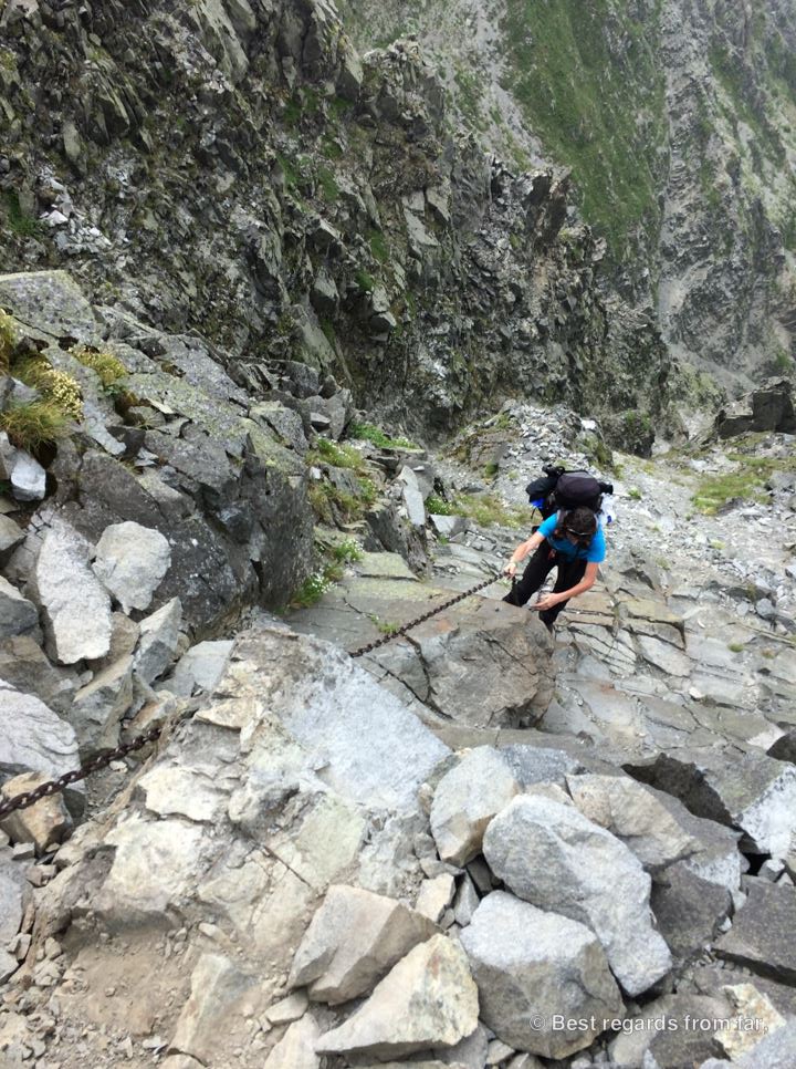 Hiker climbing up on the Daikiretto section using a long chain while hiking the Japanese Alps.