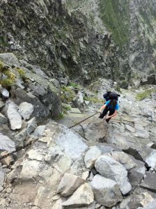 Hiker climbing up on the Daikiretto section using a long chain while hiking the Japanese Alps.