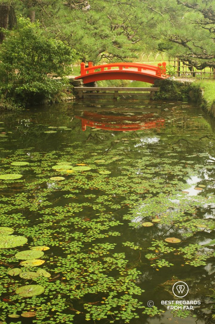 Japanese bridge over a peaceful stream in Ritsurin Gardens in Takamatsu, the most beautiful Japanese gardens in Japan.