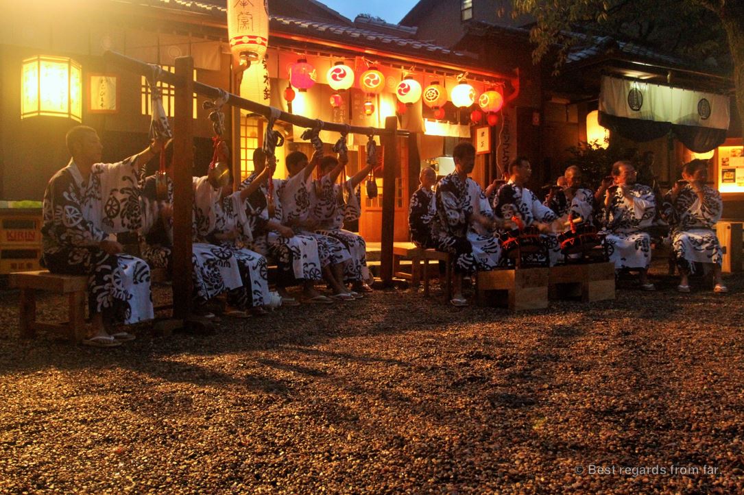 Monks in traditional outfits are playing musinc at night in fron of the Yasaka-jinja shrine in Kyoto, Japan