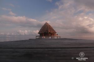 Pontoon leading to a ungalow over the turquoise water by the reef in Glover's Reef, Belize