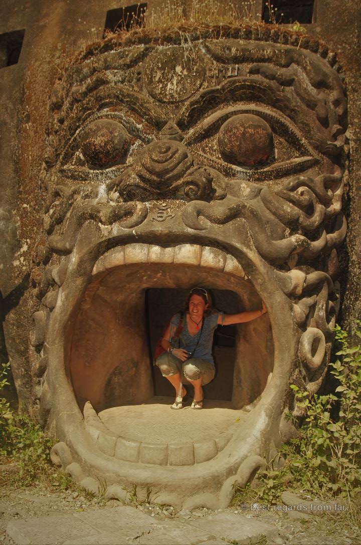 Woman posing in the mouth of a large statue.