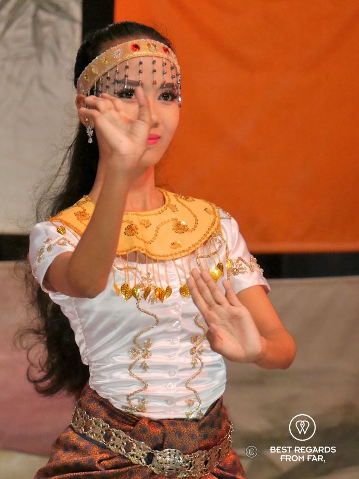 Cambodian woman dressed in traditional clothes performing a dance with her hands.