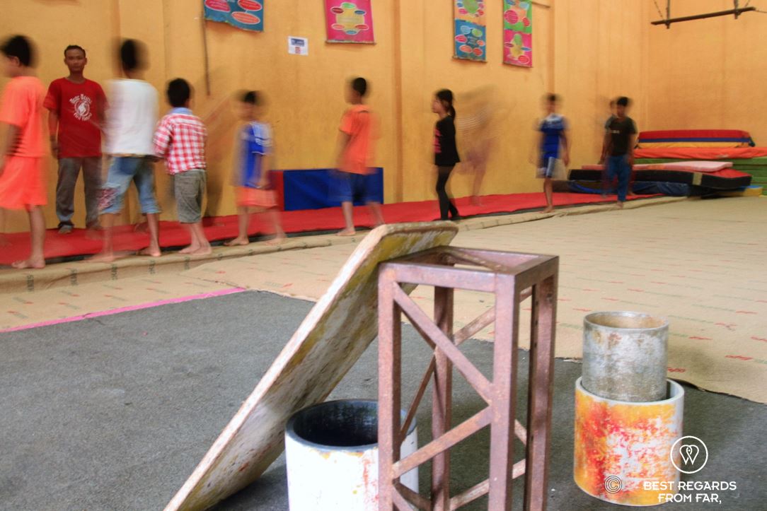A group of 8 children being taught acrobatics at a circus school.