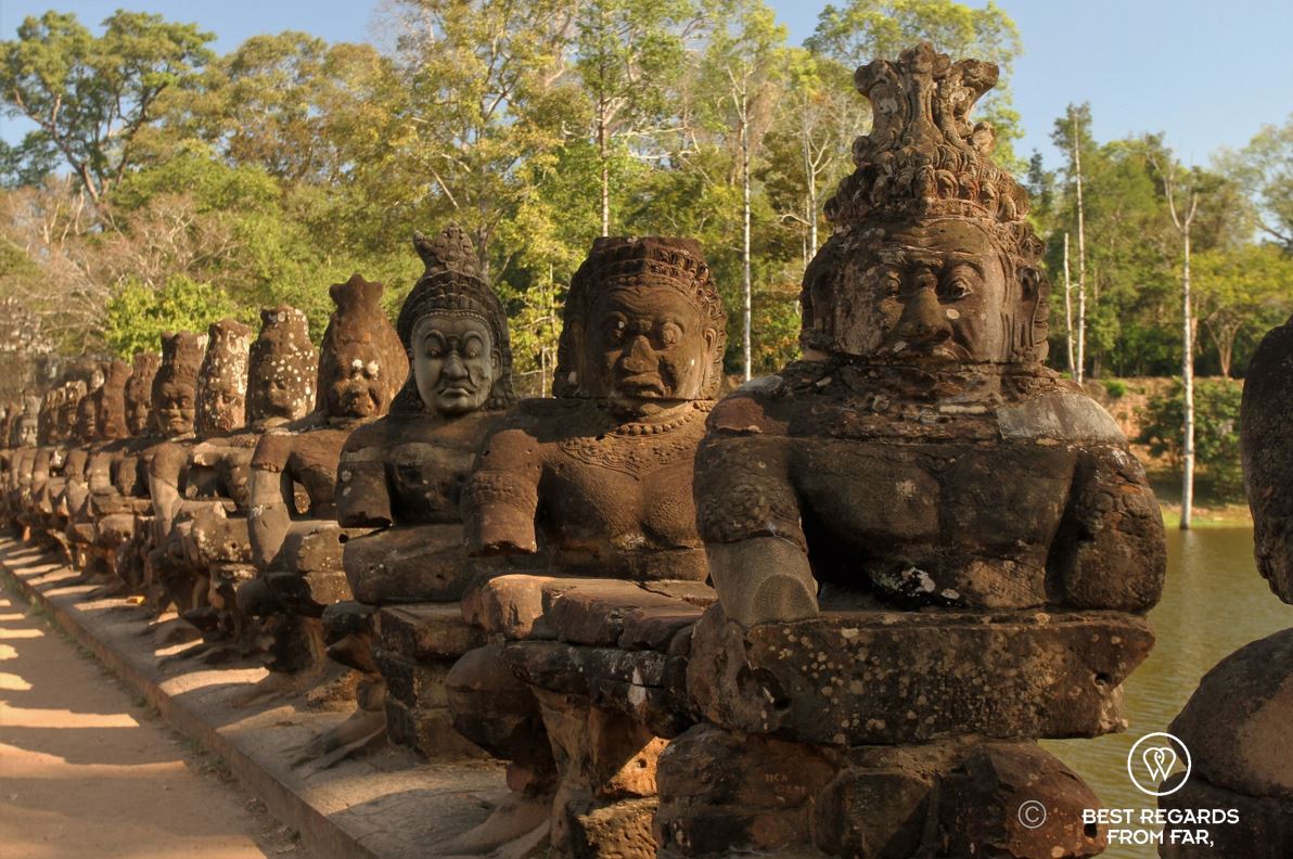 Stone demons holding a stone snake on a bridge.