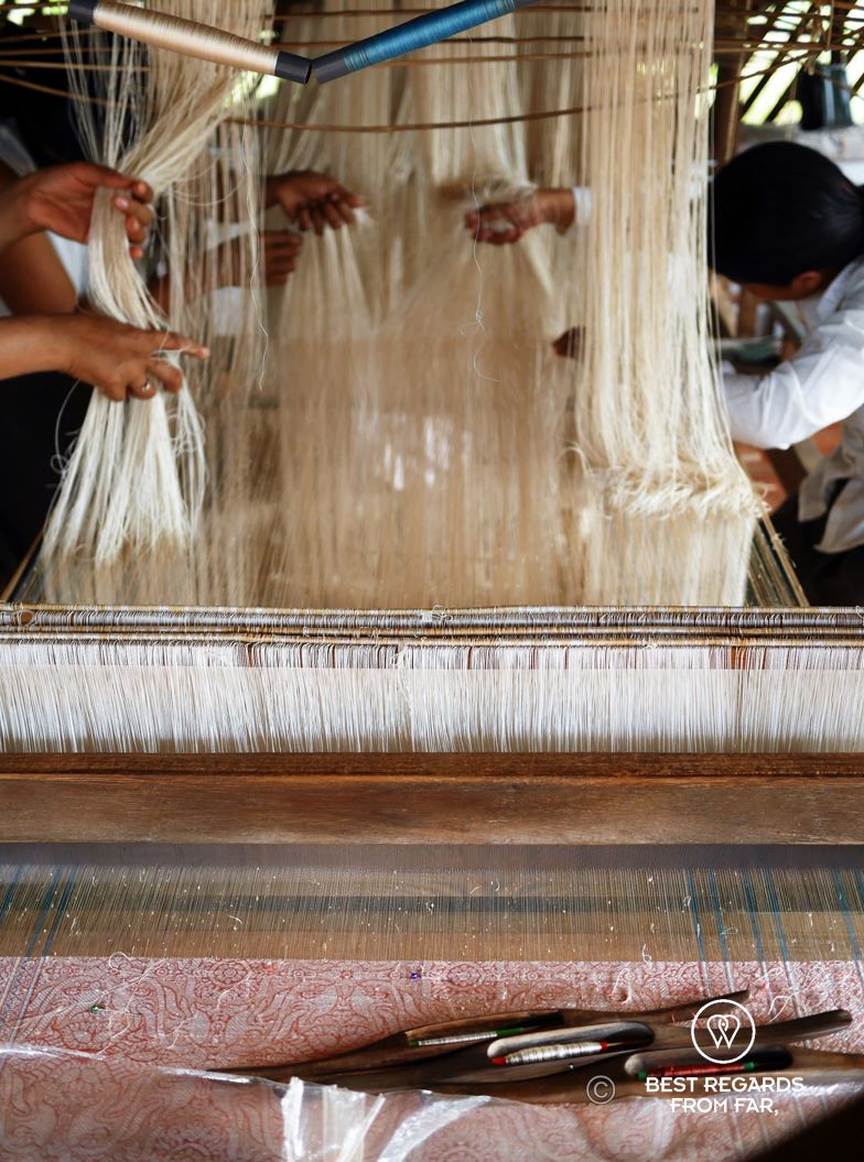 Women setting up a complicated weaving loom.