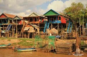 Colourful stilted wooden houses along a river bank.