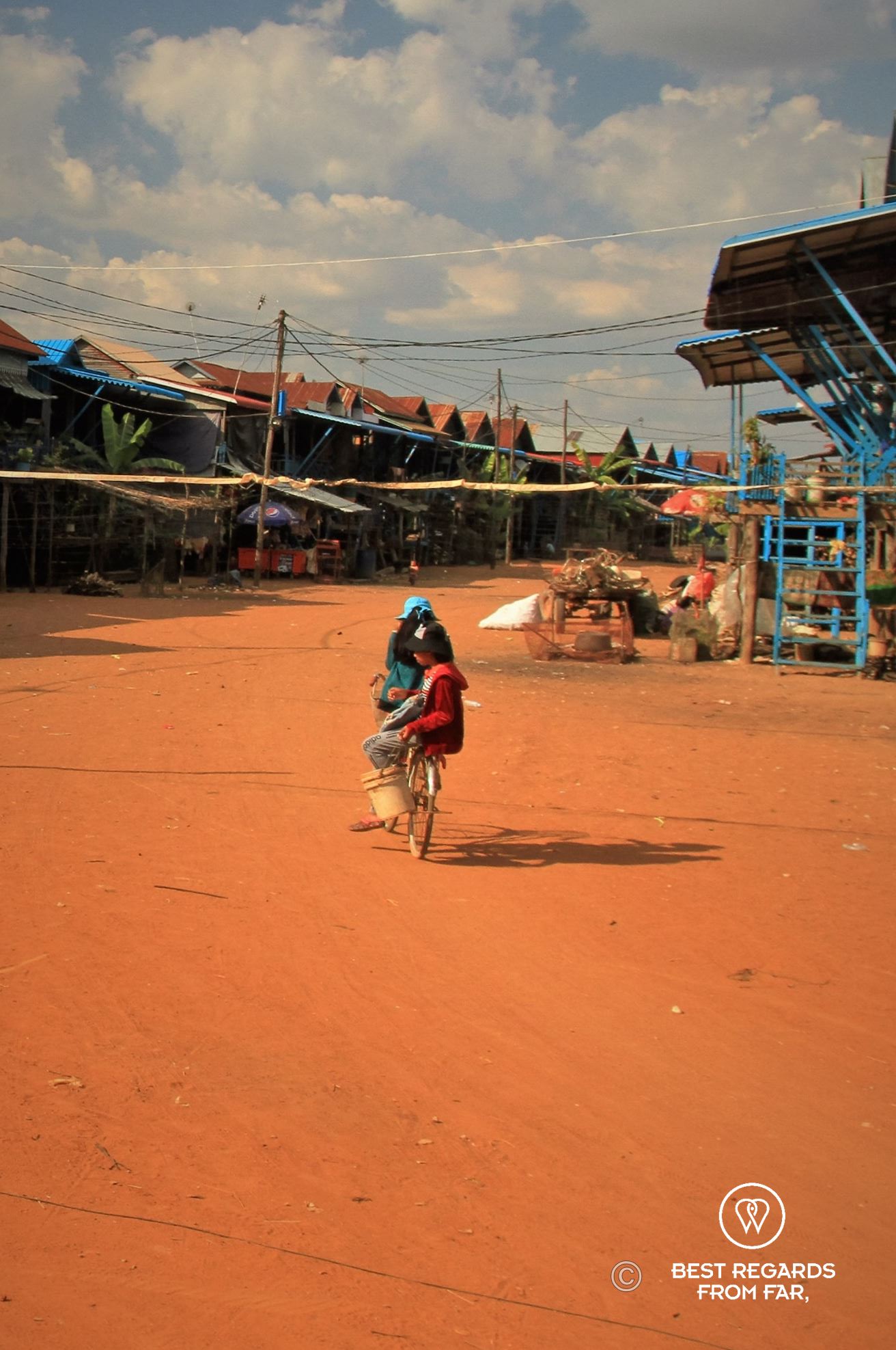 Woman on a bike on a red dirt road.