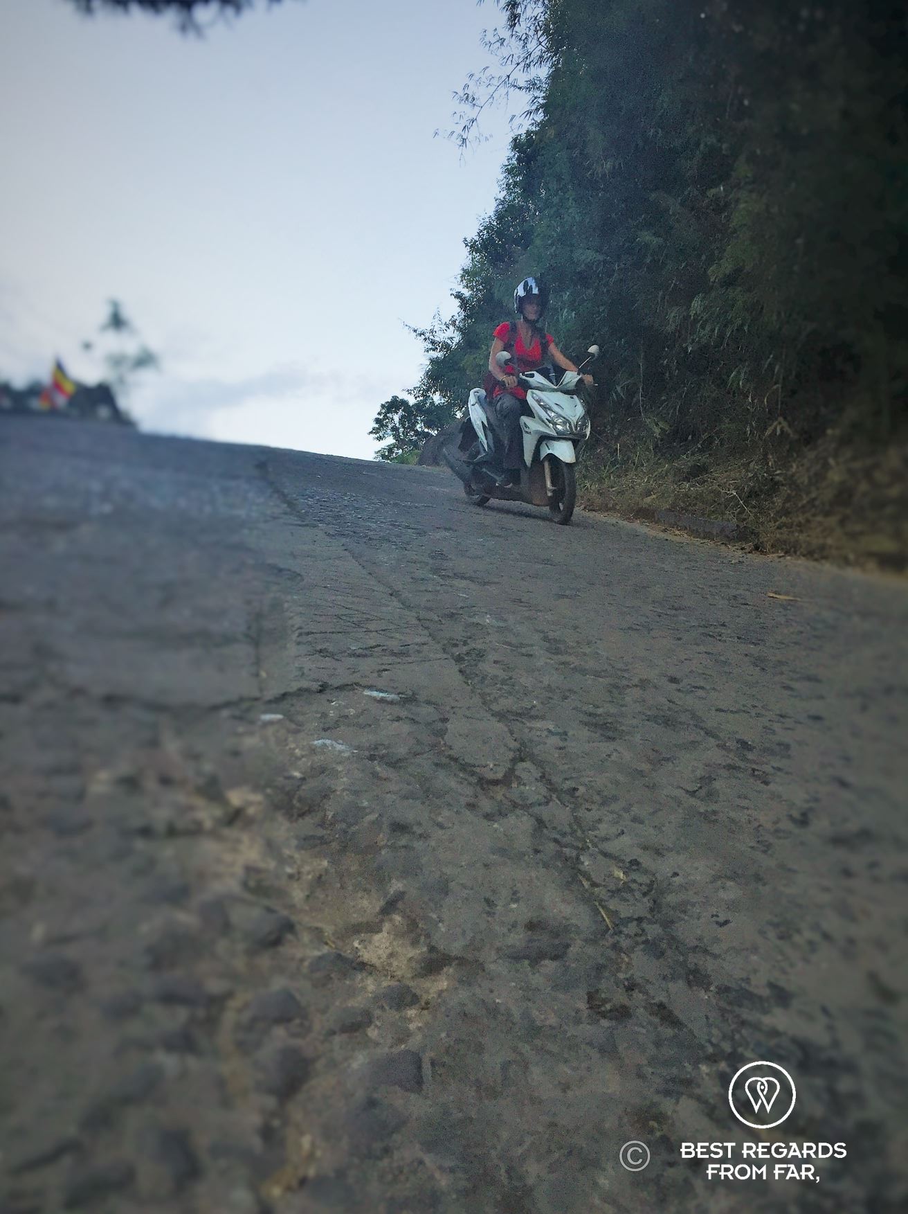 Woman driving down a scooter on a very steep asphalt road.