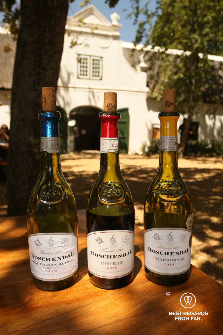 3 bottles of wine at Boschendal with a historic Cape Dutch mansion in the background, Franschhoek, South Africa.