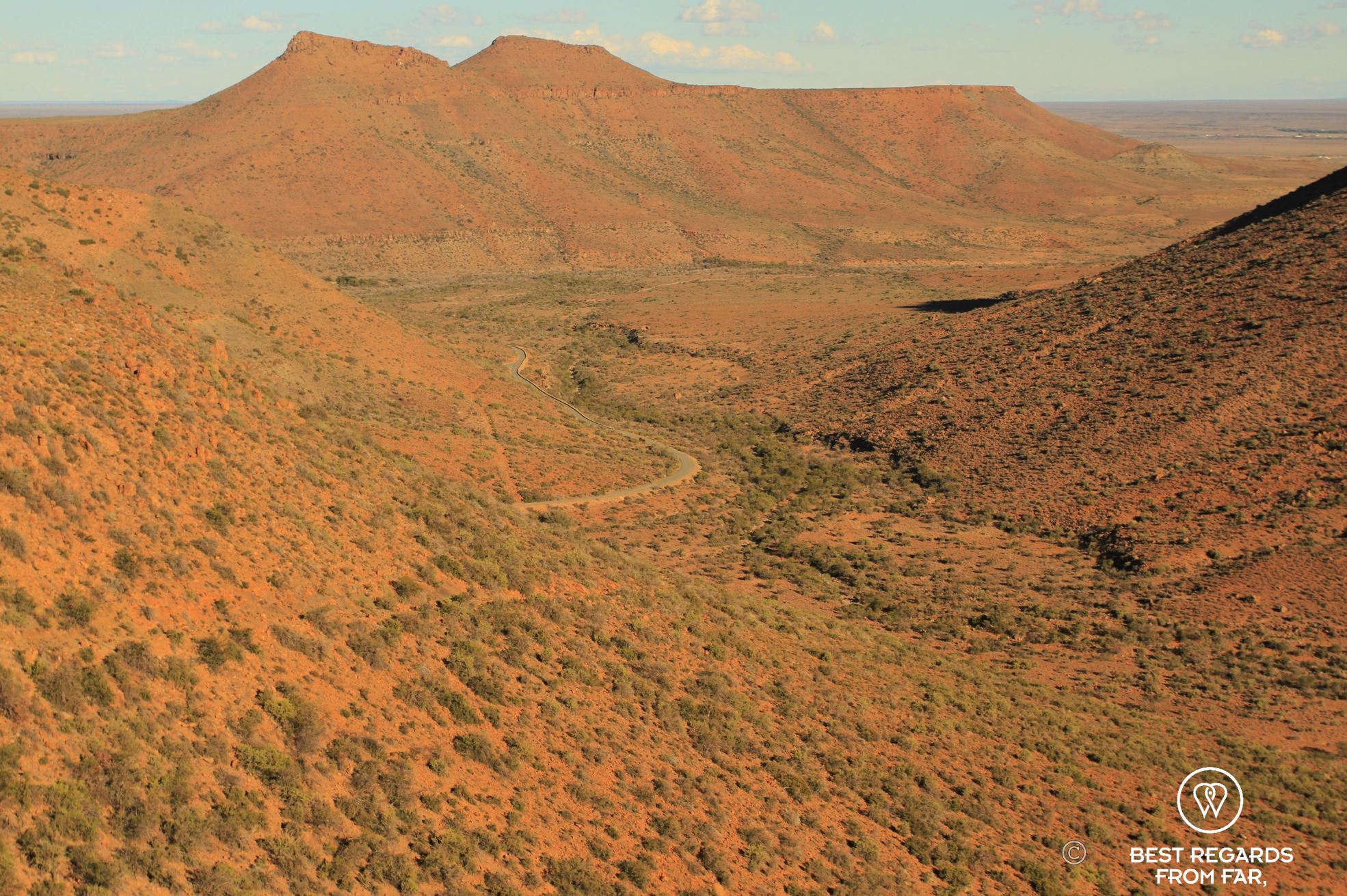 Red dry and hilly landscape with one road going through, Karoo NP, South Africa.
