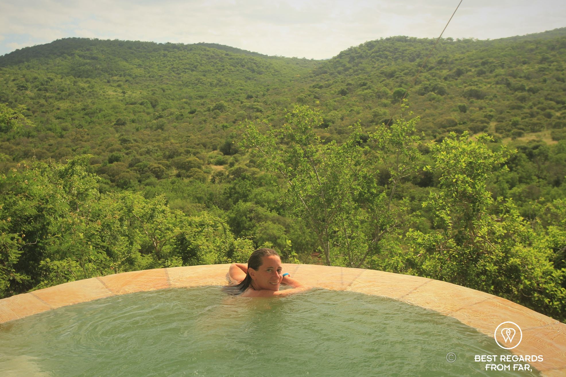 Woman in a private pool overlooking the green hills of Phinda Private Game Reserve, South Africa.