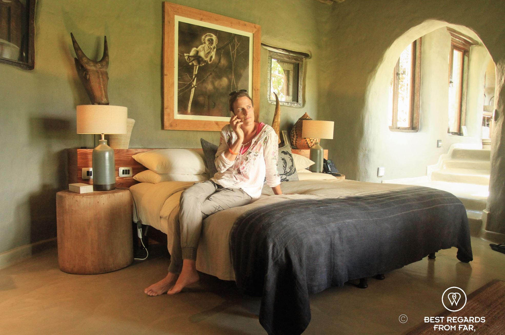 Photographer Marcella van Alphen on a bed in a luxurious room making a phone call.
