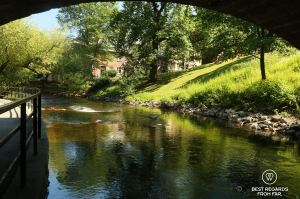 Akerselva River in Oslo wih a green slope and a house in the background.