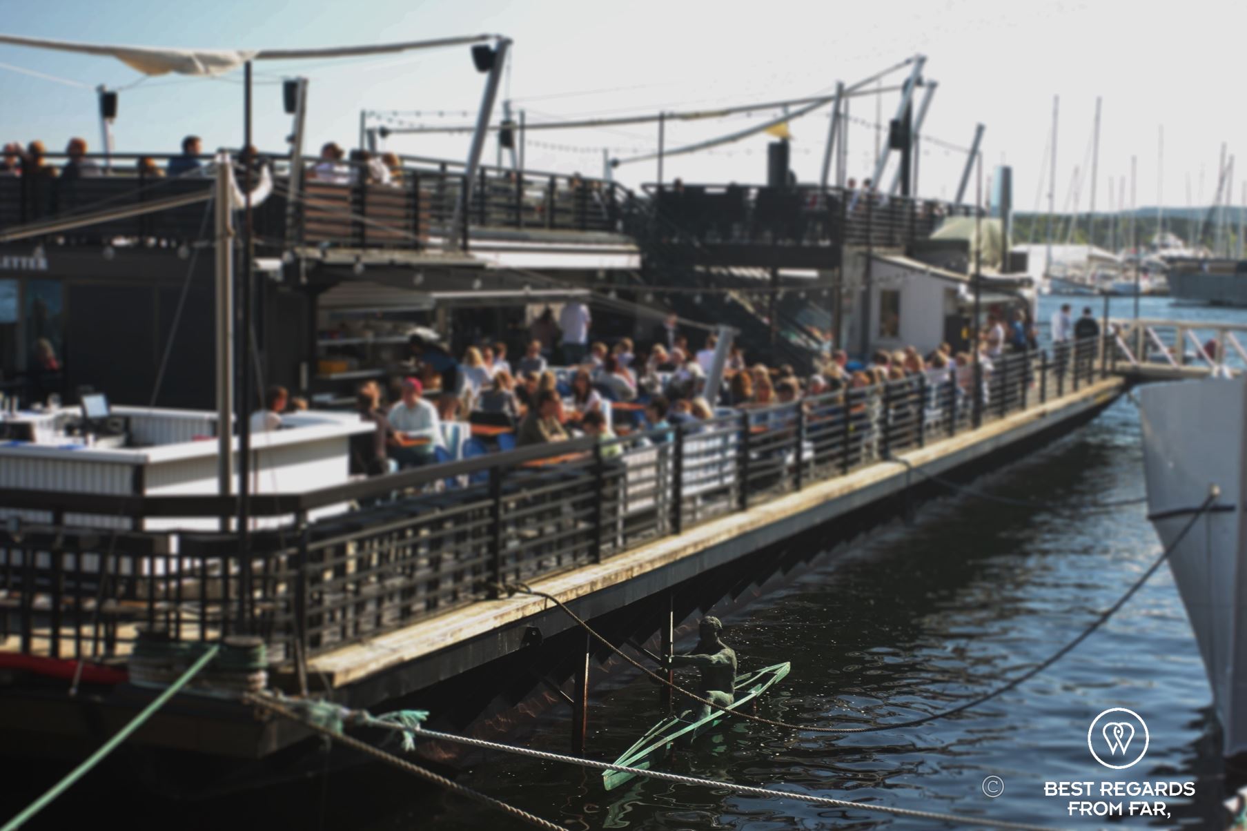 People having drinks in the sun on a large pontoon in the harbour of Oslo, Norway.