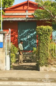 An old local man in front of the colorful colonial post office in Hell Bourg in the Salazie amphitheater on the exclusive multiday hike through the 3 cirques, Réunion Island.