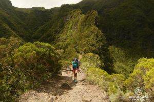 A hiker walking up the Sentier Scout in Mafate, a narrow trail along a mountain ridge on the exclusive multiday hike through the 3 cirques, Reunion Island.