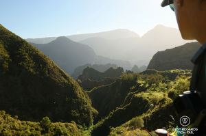A hiker in the evening sunlight overlooking layers of mountains at Ilet des Orangers in Mafate during an exclusive multiday hike through the 3 cirques, Réunion Island.