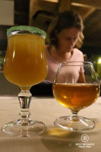 A patron at a table in a restaurant of Cilaos with a glass of punch cocktail and an infused rum, Réunion Island.