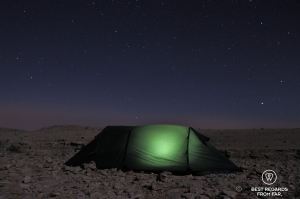 A lit mountain tent at night under the stars on the Selma Plateau high in the eastern Hajar Mountains of Oman.