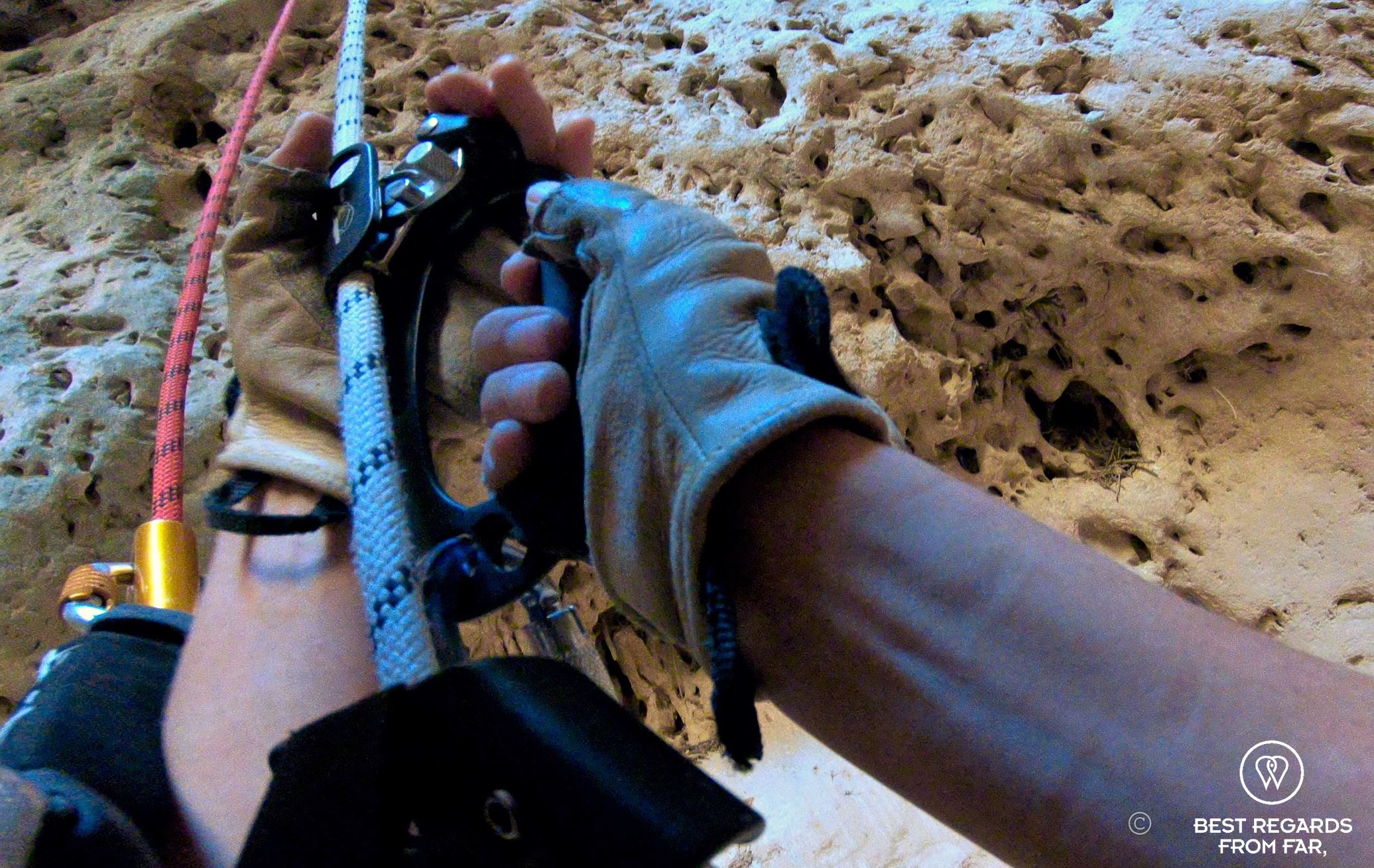 Action shot of the hands of a caver going up the Seventh Hole Cave in Oman operating the technical caving and roping gear.