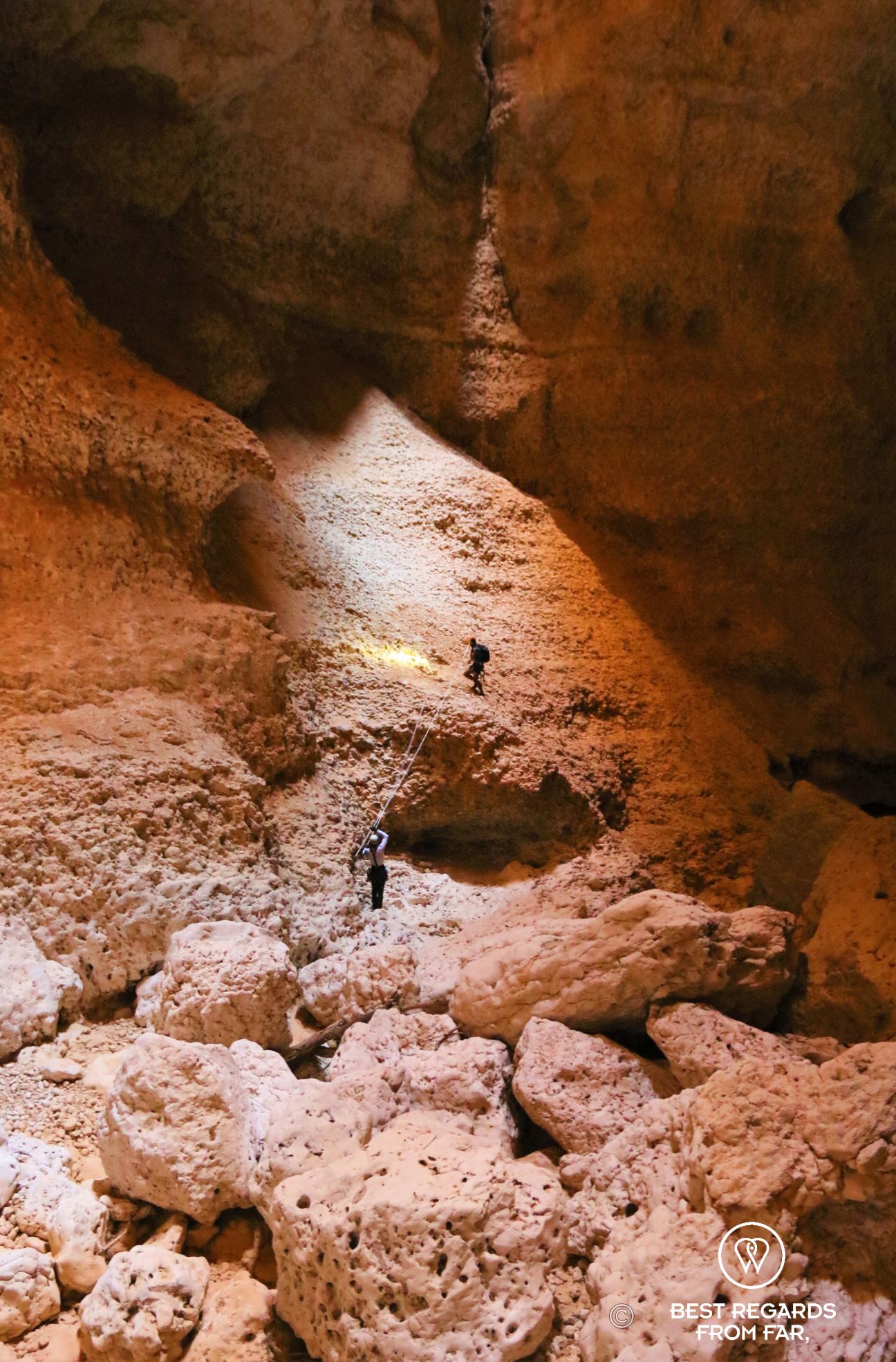 Two cavers at the bottom of the Seventh Hole Cave in Oman, including one landing after a descent on a rope.