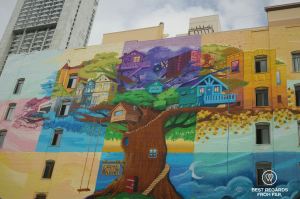 Colorful mural of a tree on dull building.