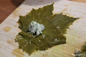 Vine leaf with stuffing on a wooden board during a cooking class in Greece.