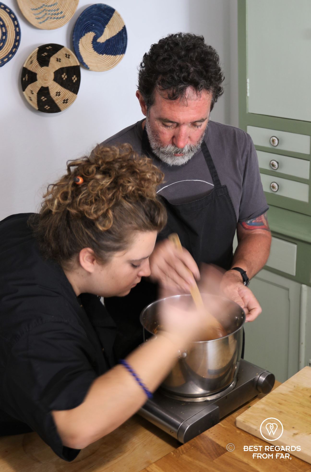 Man and woman cooking above a stove.
