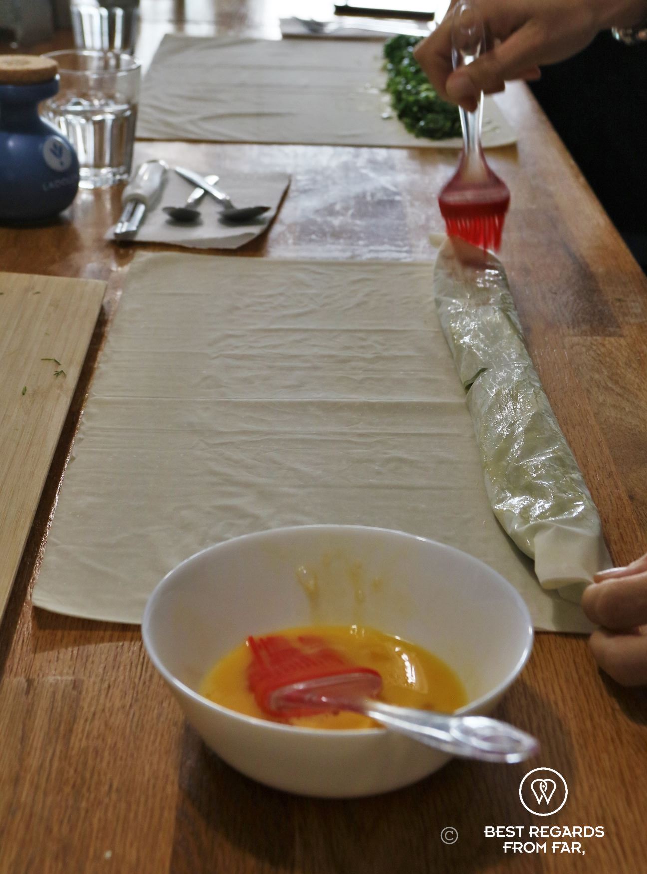 White bowl with egg yawlk and a thin dough spread on a table.