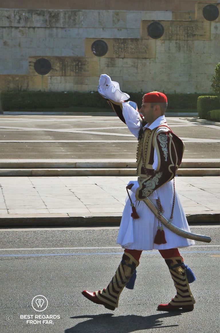 Man dressed in traditional clothes marching a square during the changing of the guards in Athens.
