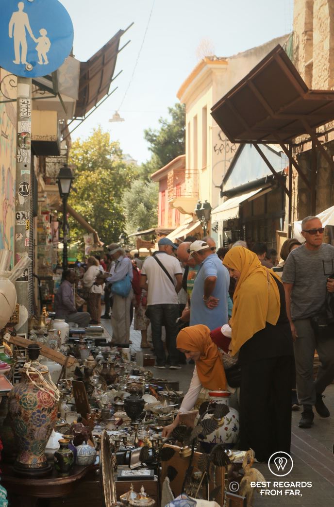 People walking a flea market in Athens on a sunny day.