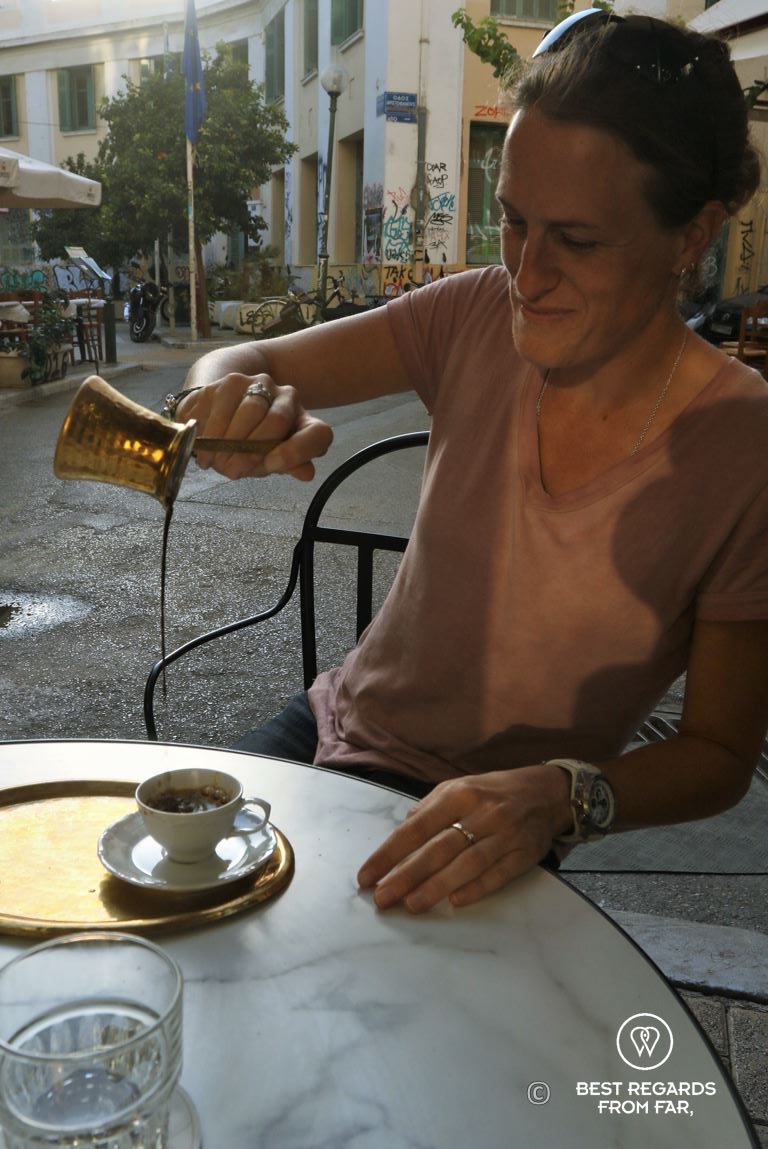 Woman pouring Greek coffee from high into a small cup on a terrace in Athens.