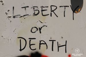 Black graffiti on a white wall reading Liberty or Death during the Hong Kong protests