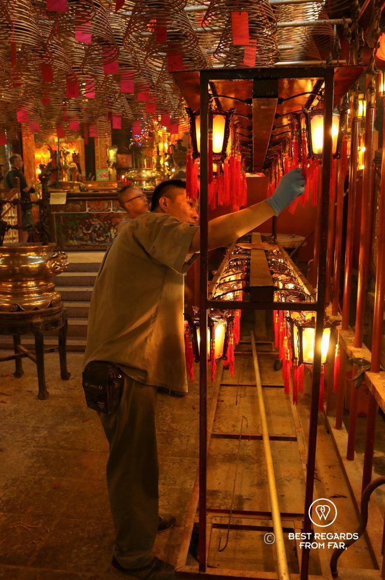 Monk arranging candles at the Man Mo Temple on Hong Kong Island. Red and gold tones dominate.