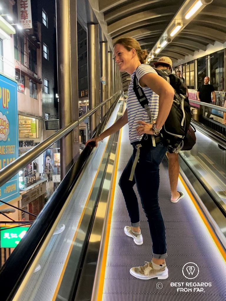 Smiling tourists riding the mid-levels escalators to go up on Hong Kong Island