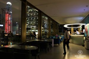 Waiter and patrons at the Popinjays stylish rooftop cocktail bar at night with lit towers, the luxurious Murray Hotel, Hong Kong Island