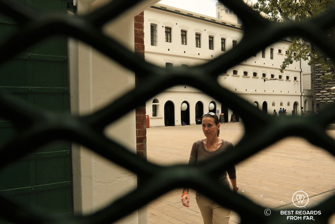 Visitor in the prison courtyard behind a fence at the former police quarters at Tai Kwun turned into a museum, Hong Kong