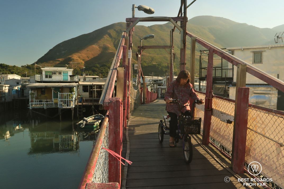 Local woman on a tricycle crossing a red bridge, Tai O fishing village, Lantau Island, Hong Kong