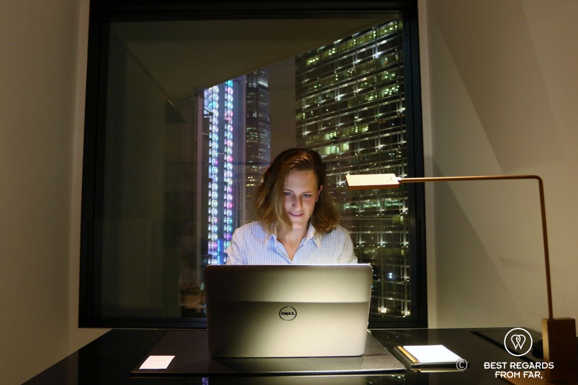 Guest at the desk in a hotel room of the luxurious Murray hotel on Hong Kong Island working on a laptop at night