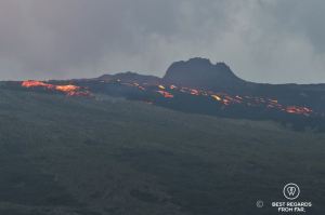 The Furnace Peak volcano in eruption in with the bright red lava in fusion flowing down the dark basalt slopes