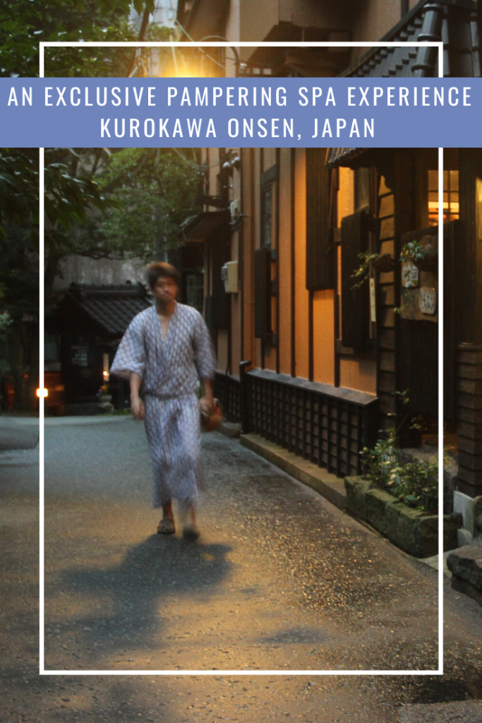Japanese man in a kimono walking on wet asphalt along traditional Japanese houses in Kurokawa,