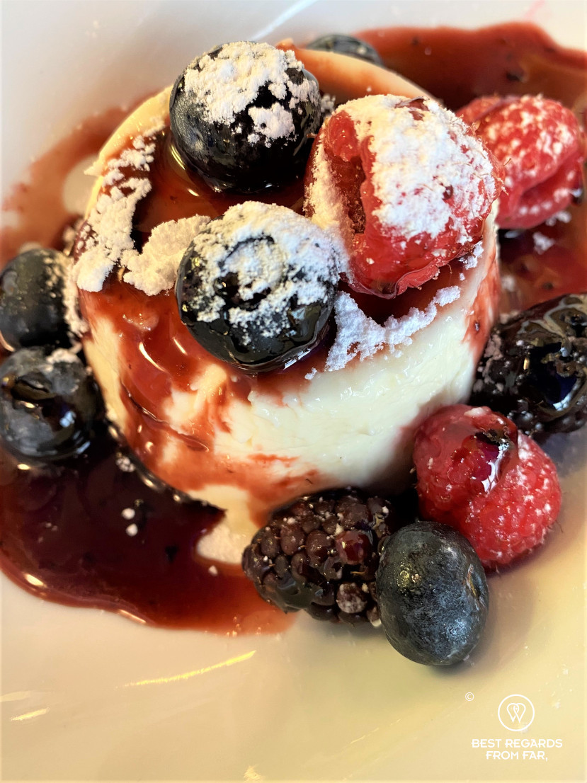 Panna cotta desert with red beries and white sugat on top
