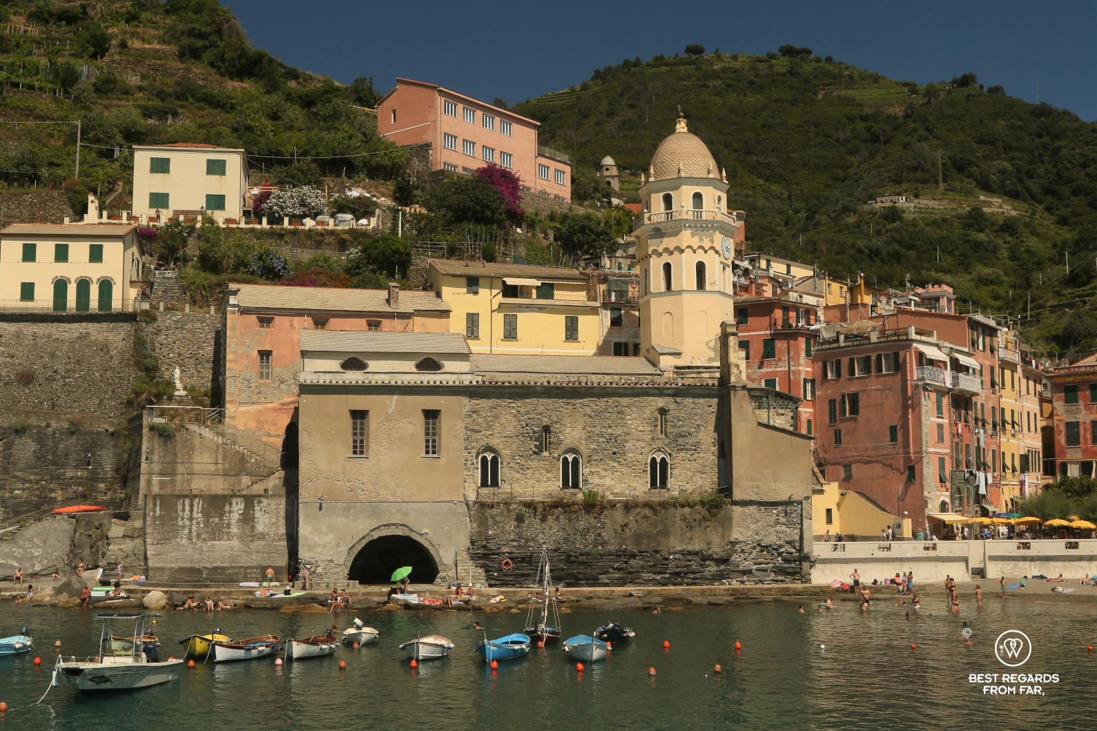 Small boats in the harbour of Vernazza, Italy with old houses and green mountains