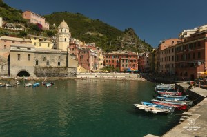Boats in the quiet harbour of Cinque Terre with green mountains and blue skies
