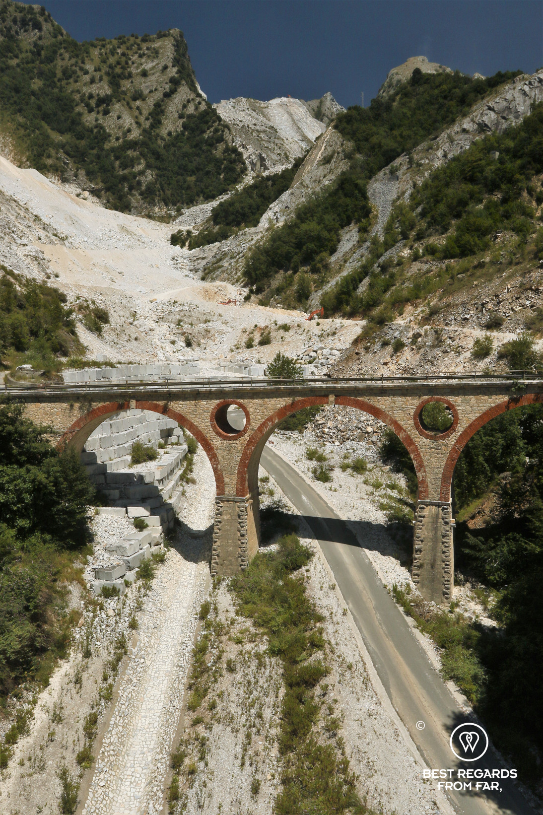 Old bridge over a white road in the mountains of Carrara, Italy