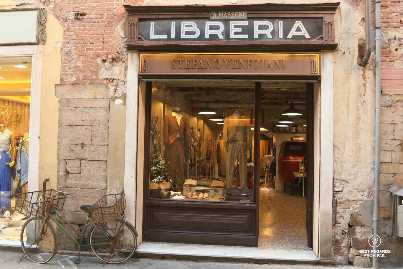 A green rusty bike parked in front of a clothing store in Lucca, Italy