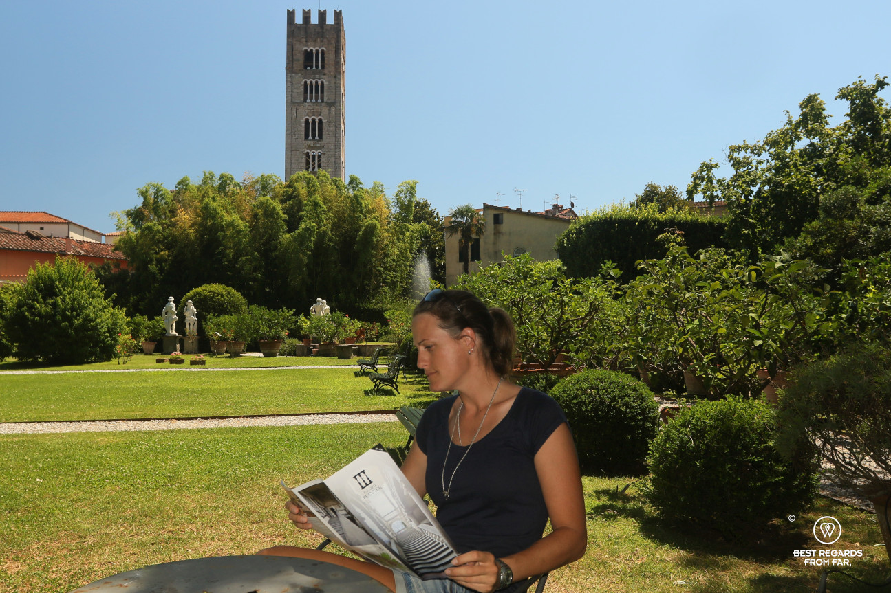 Woman reading a brochure in the green garden of the Pfanner palace, Lucca